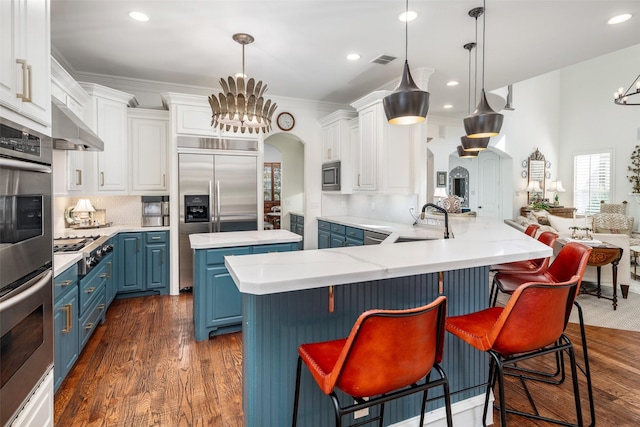 kitchen with blue cabinets, visible vents, a sink, an inviting chandelier, and built in appliances