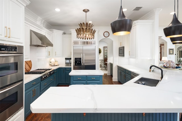 kitchen featuring visible vents, arched walkways, a sink, built in appliances, and blue cabinets