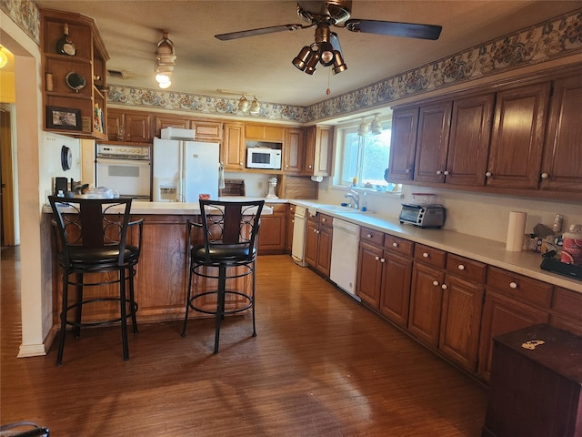 kitchen featuring a breakfast bar, sink, a center island, dark hardwood / wood-style flooring, and white appliances