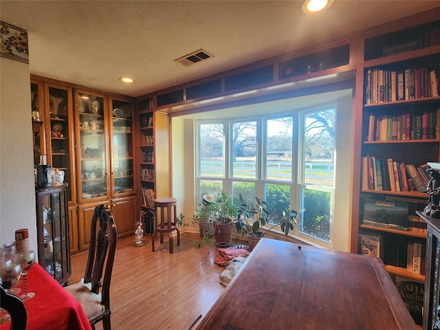 office space with built in shelves and wood-type flooring