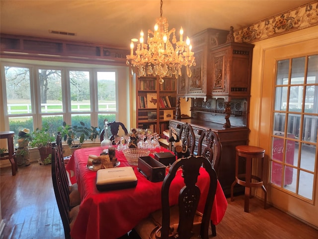 dining space with hardwood / wood-style flooring and a chandelier