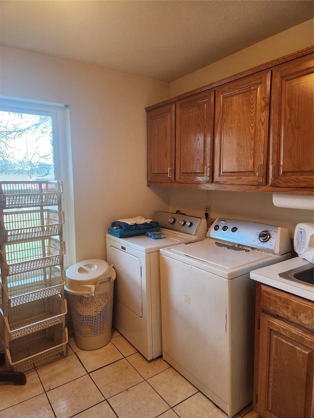 laundry room featuring washer and dryer, light tile patterned floors, cabinets, and a textured ceiling