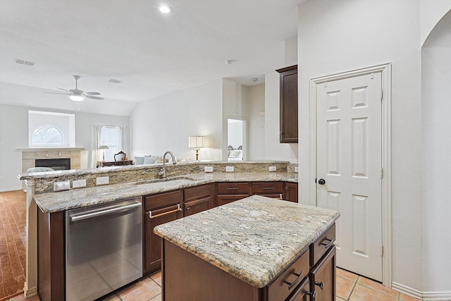 kitchen with lofted ceiling, light stone countertops, a kitchen island, stainless steel dishwasher, and sink