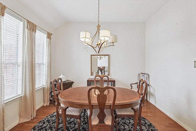 dining room featuring hardwood / wood-style flooring, lofted ceiling, and a chandelier