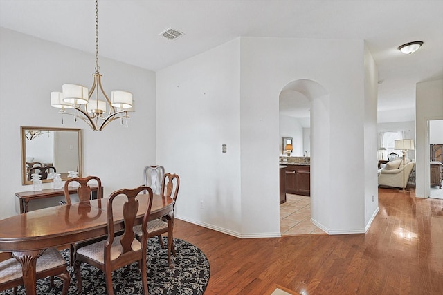 dining room with light hardwood / wood-style flooring and an inviting chandelier