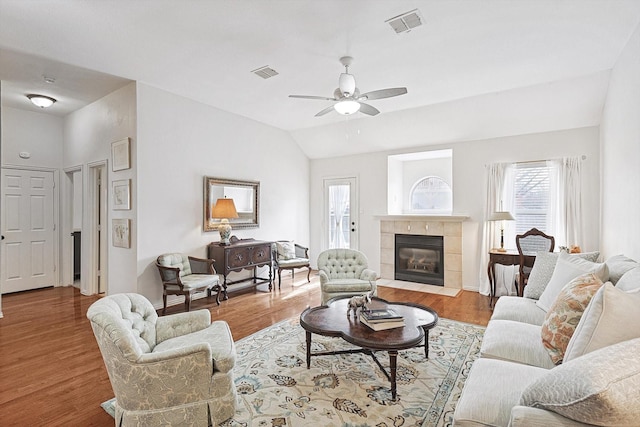 living room featuring light wood-type flooring, ceiling fan, vaulted ceiling, and a fireplace