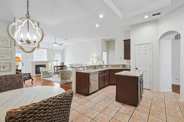 kitchen featuring decorative light fixtures, dishwasher, kitchen peninsula, sink, and a tiled fireplace