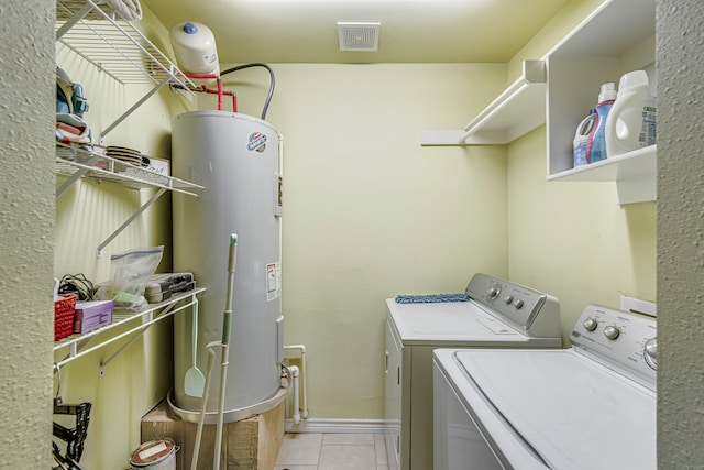 clothes washing area featuring water heater, separate washer and dryer, and light tile patterned floors