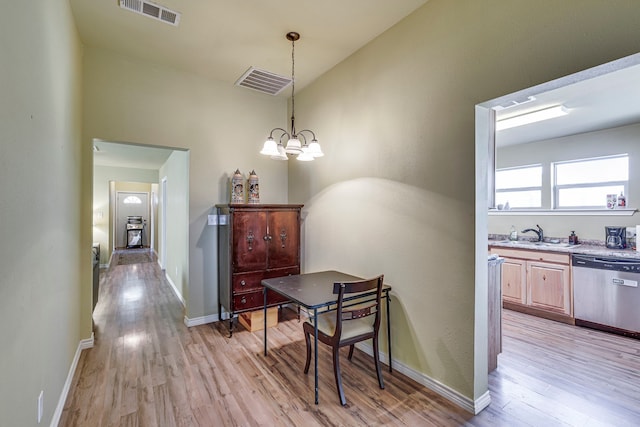 dining area with light wood-type flooring, sink, and a notable chandelier