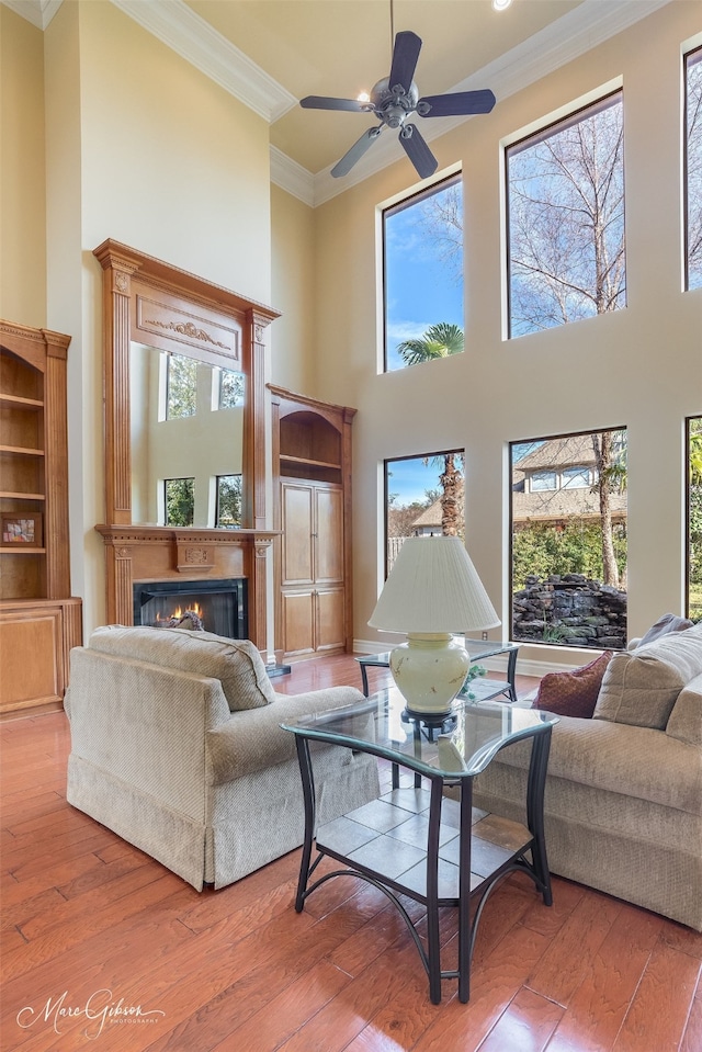 1069 Waters Edge Cir, Shreveport, LA 71106 - living area with ornamental molding, a high ceiling, hardwood / wood-style flooring, a warm lit fireplace, and ceiling fan