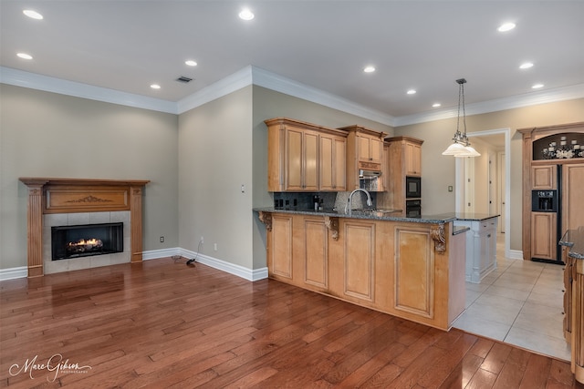 kitchen featuring decorative light fixtures, kitchen peninsula, sink, a breakfast bar area, and dark stone counters