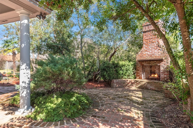 view of yard featuring a patio area and an outdoor brick fireplace