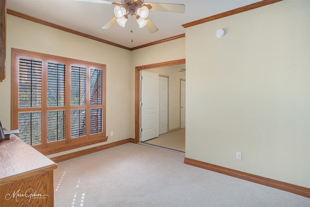 carpeted spare room featuring ceiling fan and crown molding