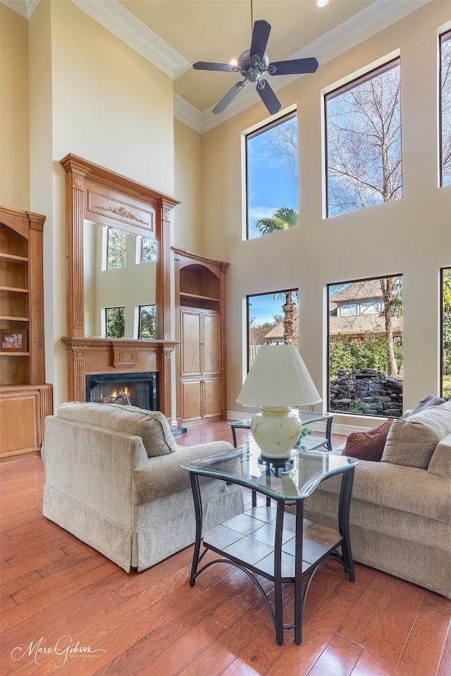 living room with a high ceiling, wood-type flooring, and crown molding