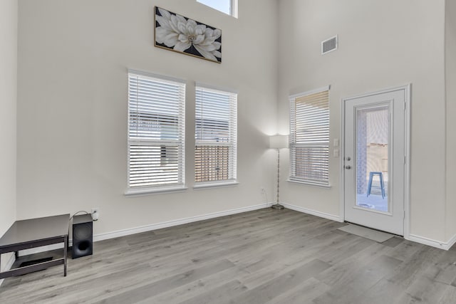 entryway with light hardwood / wood-style flooring and a towering ceiling