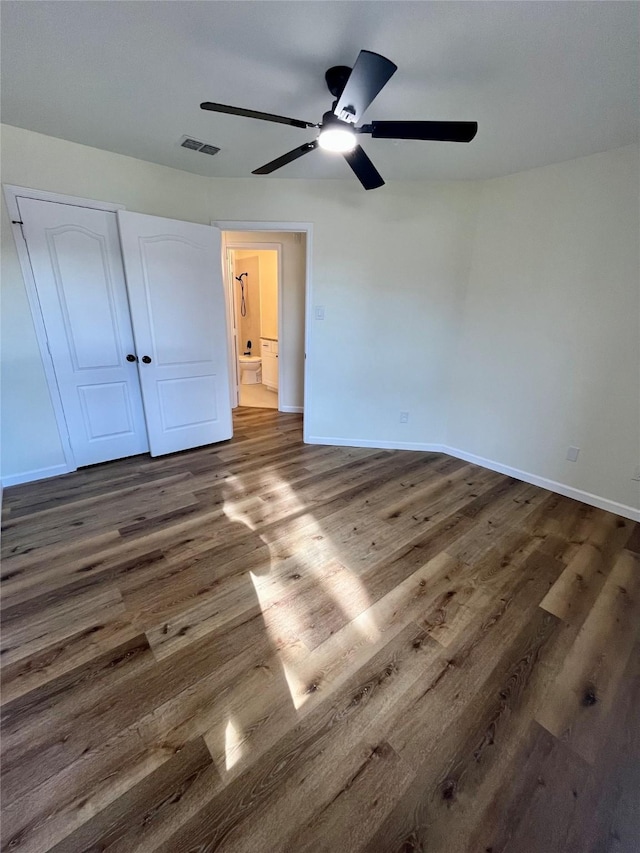 unfurnished bedroom with ceiling fan, dark hardwood / wood-style flooring, and a closet