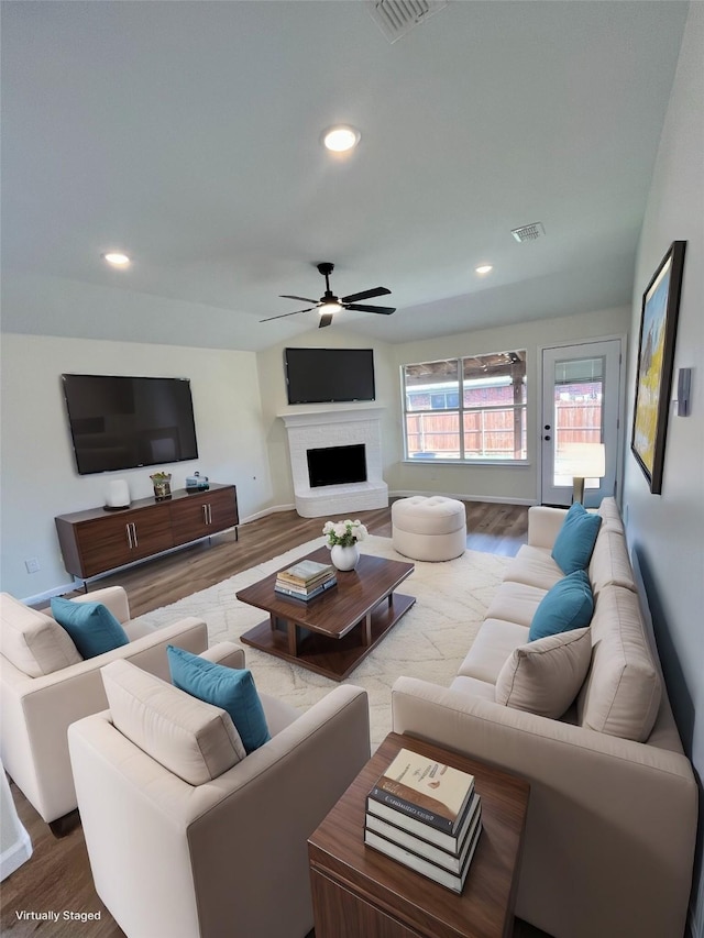 living room with hardwood / wood-style flooring, a brick fireplace, and ceiling fan