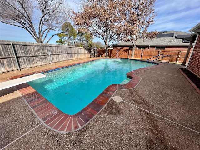 view of swimming pool with a diving board and a patio