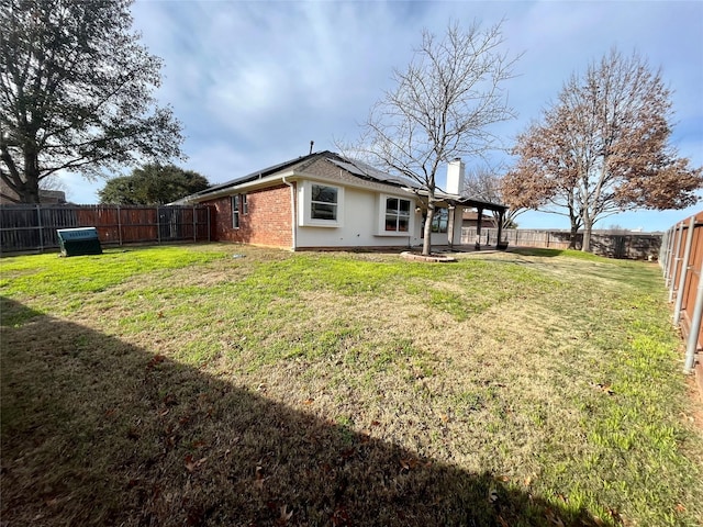 rear view of property with solar panels and a yard