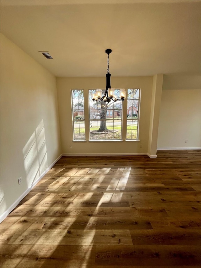 unfurnished dining area with dark wood-type flooring and a notable chandelier