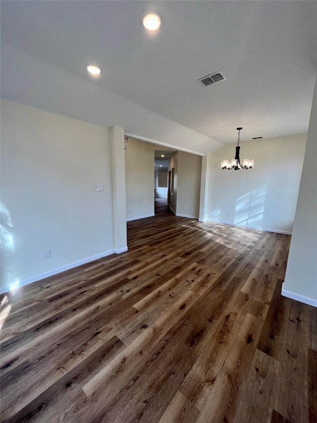 unfurnished room with dark hardwood / wood-style floors, lofted ceiling, and a chandelier