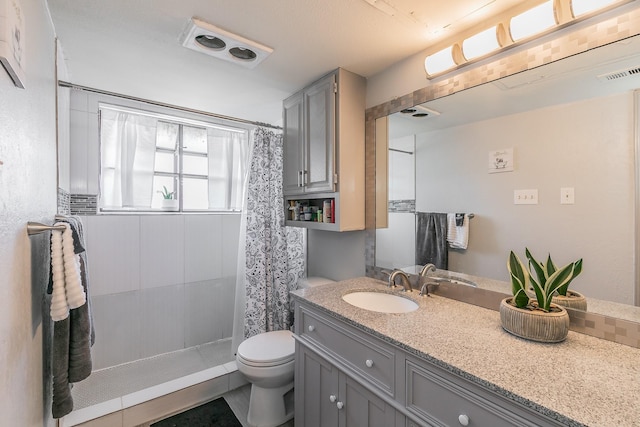 bathroom featuring toilet, vanity, and walk in shower