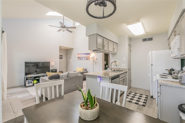 dining room featuring ceiling fan, a skylight, light hardwood / wood-style flooring, and sink