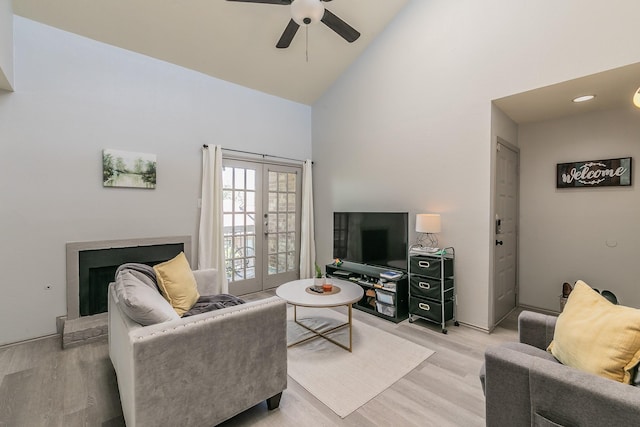 living room with light wood-type flooring, ceiling fan, french doors, and high vaulted ceiling