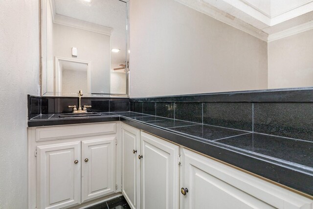 kitchen with white cabinetry, black appliances, light tile patterned floors, a raised ceiling, and backsplash