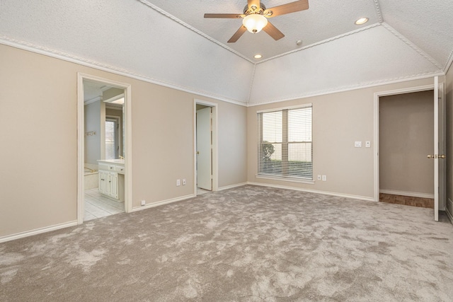 unfurnished bedroom featuring connected bathroom, lofted ceiling, ornamental molding, light carpet, and a textured ceiling