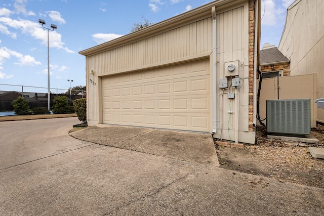 garage with central AC, fence, and driveway