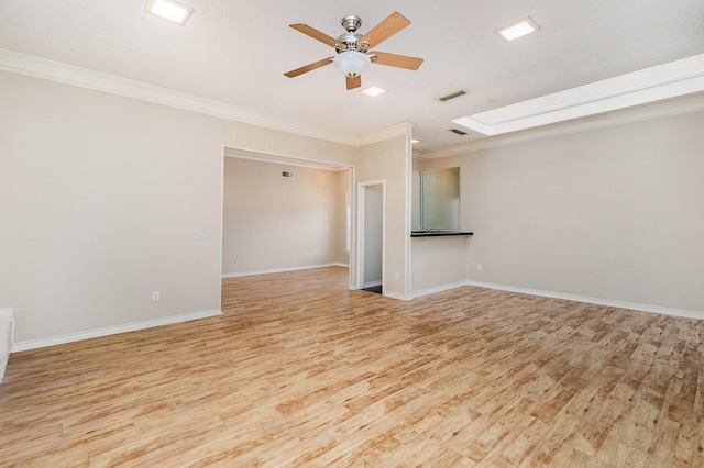 empty room with a skylight, visible vents, crown molding, and light wood-style flooring