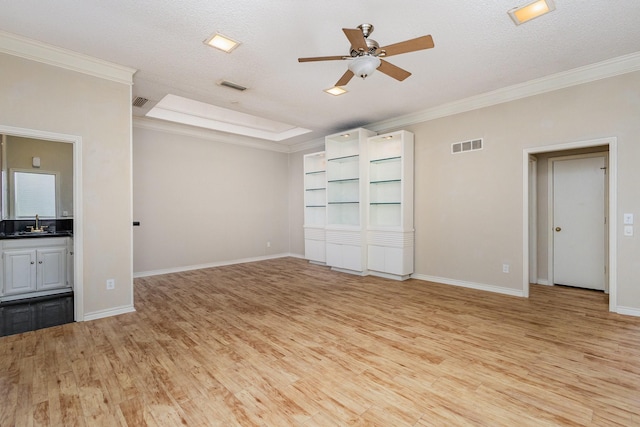 unfurnished living room featuring ornamental molding, ceiling fan, a textured ceiling, and light wood-type flooring