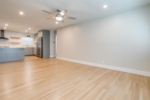 unfurnished living room with light hardwood / wood-style floors, sink, and ceiling fan