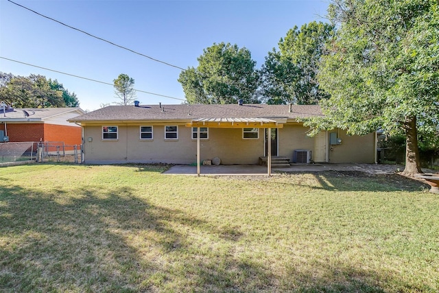 rear view of house with central air condition unit, a lawn, and a patio