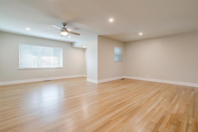 spare room featuring ceiling fan, a wealth of natural light, and light wood-type flooring