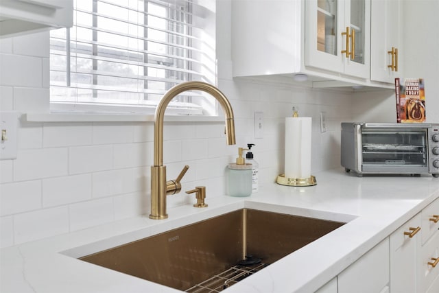 details with white cabinetry, sink, and tasteful backsplash