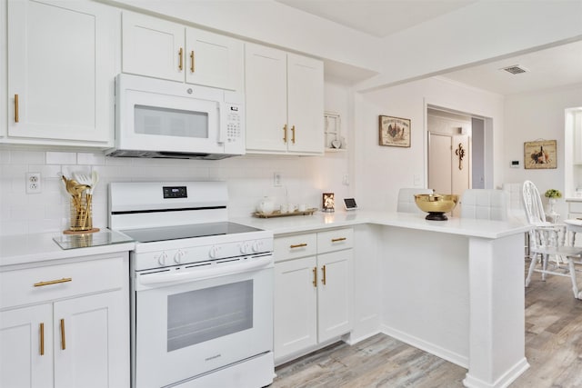 kitchen with white appliances, kitchen peninsula, and white cabinets