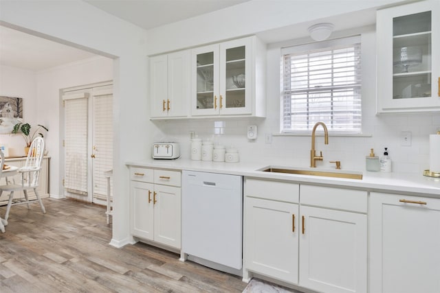 kitchen with sink, dishwasher, white cabinetry, backsplash, and light wood-type flooring