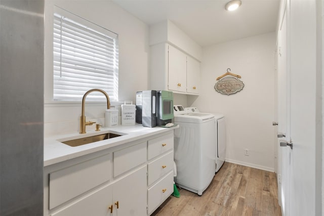 clothes washing area with sink, cabinets, washing machine and dryer, and light hardwood / wood-style floors