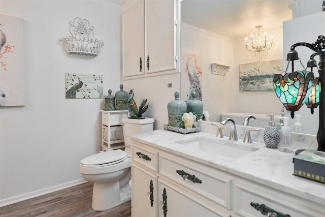 bathroom with hardwood / wood-style floors, vanity, a notable chandelier, ornamental molding, and toilet