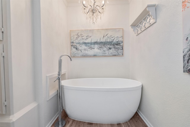 bathroom with crown molding, an inviting chandelier, a tub, and hardwood / wood-style flooring