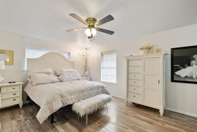 bedroom featuring ceiling fan, hardwood / wood-style floors, and a textured ceiling