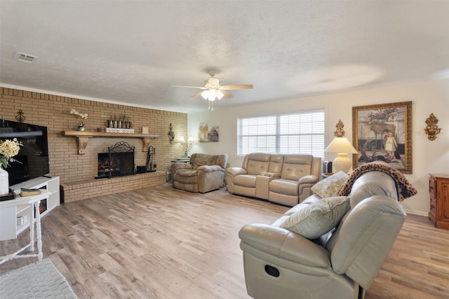 living room with a brick fireplace, wood-type flooring, a textured ceiling, and brick wall