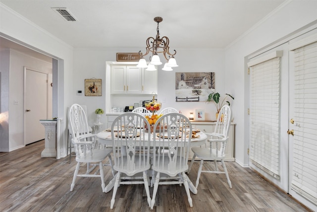 dining room with crown molding, wood-type flooring, and a chandelier