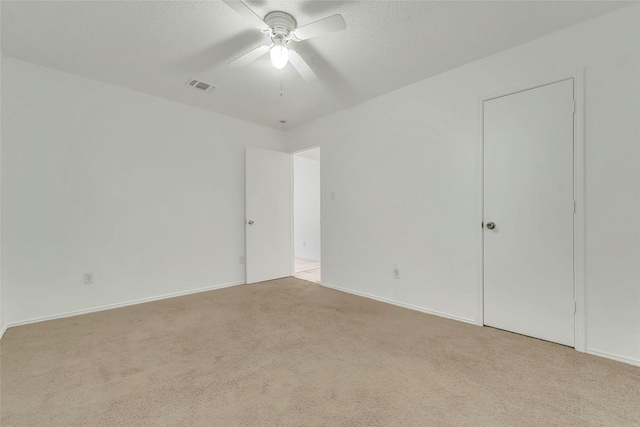 unfurnished bedroom with ceiling fan, light colored carpet, and a textured ceiling