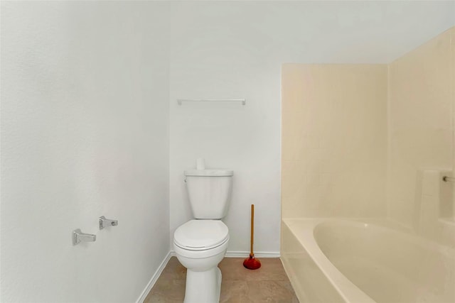 bathroom with a tub to relax in, tile patterned floors, and toilet