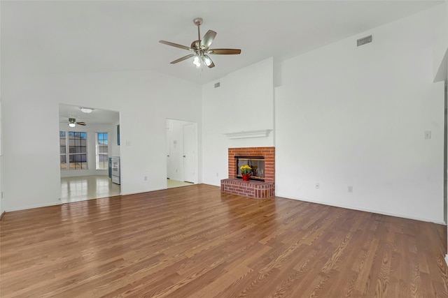 unfurnished living room featuring lofted ceiling, hardwood / wood-style floors, a fireplace, and ceiling fan