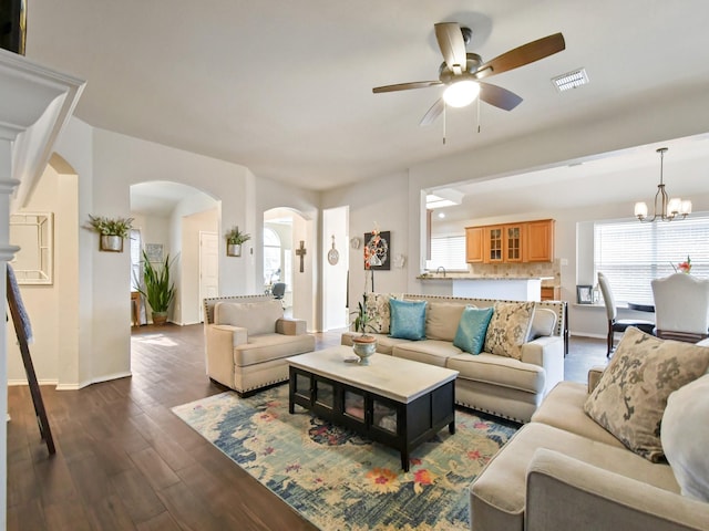 living room featuring ceiling fan with notable chandelier and dark hardwood / wood-style floors