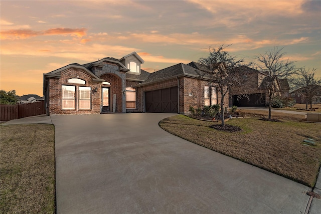 french country inspired facade featuring a garage and a yard